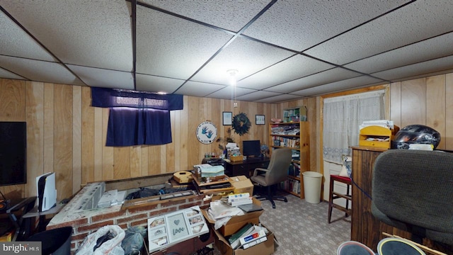 home office featuring a drop ceiling, carpet flooring, and wooden walls