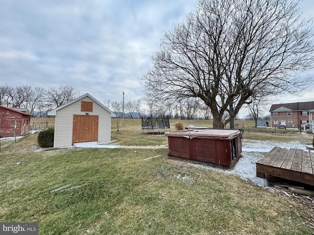 view of yard with a trampoline, an outdoor structure, a hot tub, and a storage shed