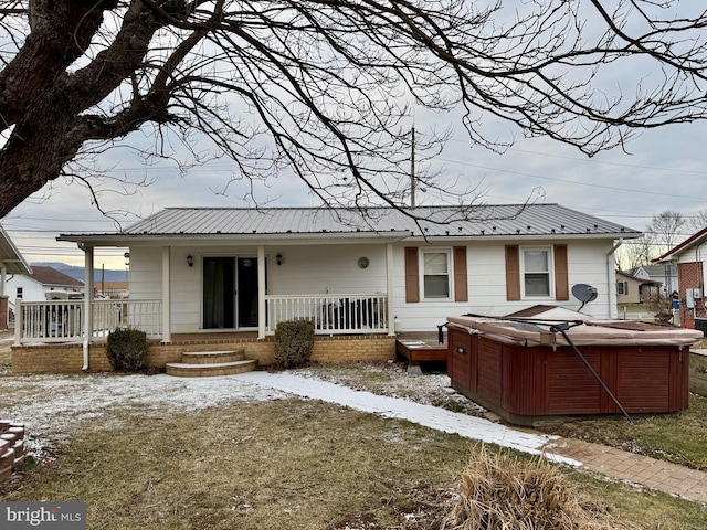 back of property with a porch, metal roof, and a hot tub