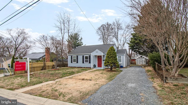 bungalow featuring a front yard, an outbuilding, a shed, and fence