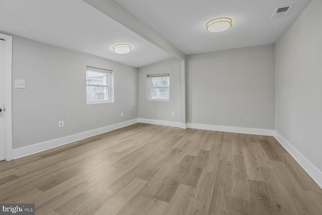 empty room with beamed ceiling, baseboards, visible vents, and light wood-type flooring