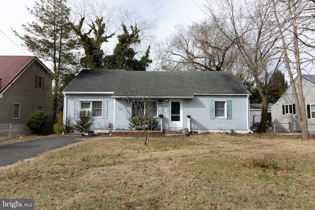 view of front of house featuring driveway, a shingled roof, fence, and a front yard