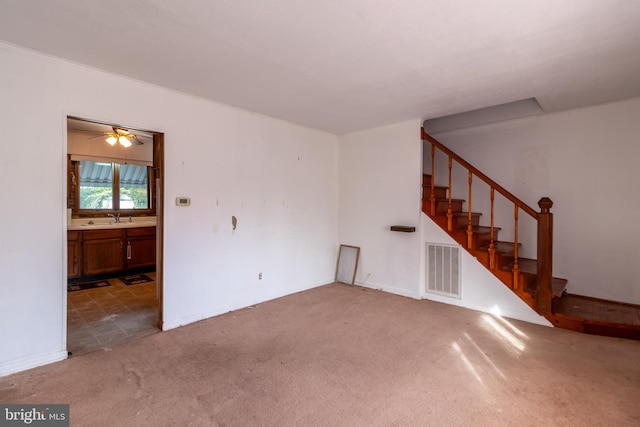 empty room with carpet, visible vents, a sink, and stairway