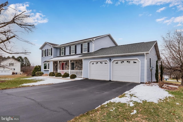 traditional home featuring an attached garage, covered porch, driveway, and stone siding