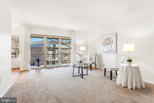 sitting room featuring baseboards, visible vents, and light colored carpet