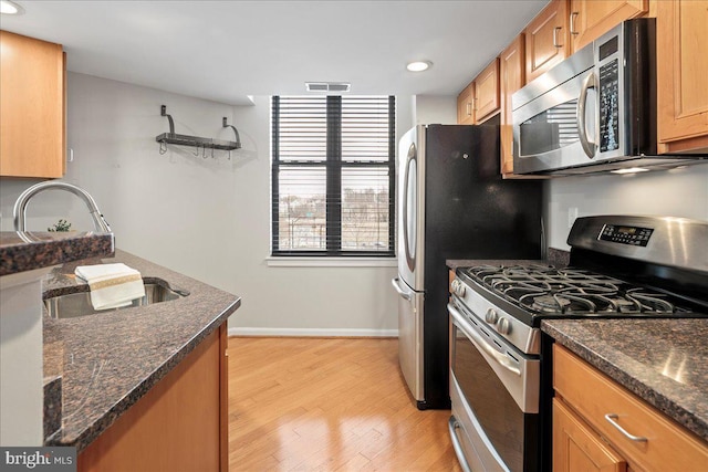 kitchen with light wood-type flooring, visible vents, appliances with stainless steel finishes, and dark stone countertops