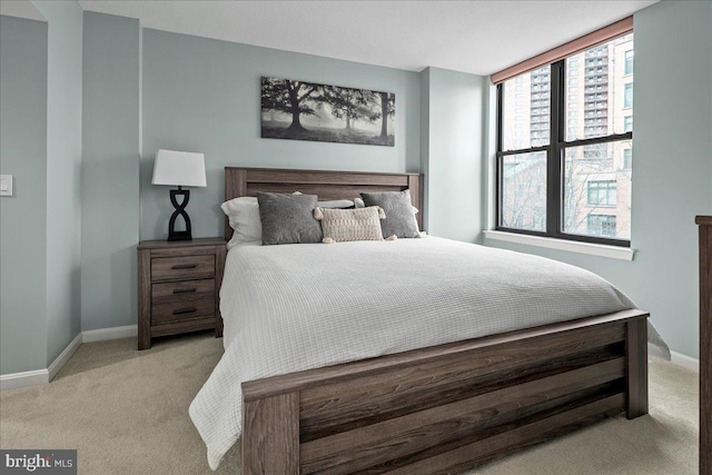 bedroom with baseboards and light colored carpet