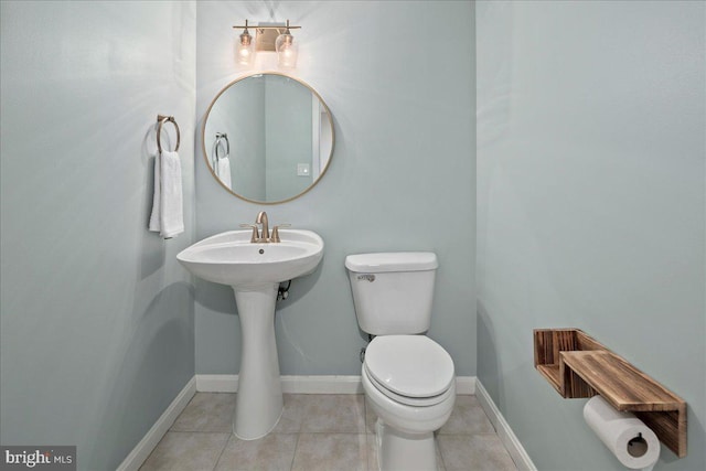 half bath with tile patterned flooring, toilet, and baseboards