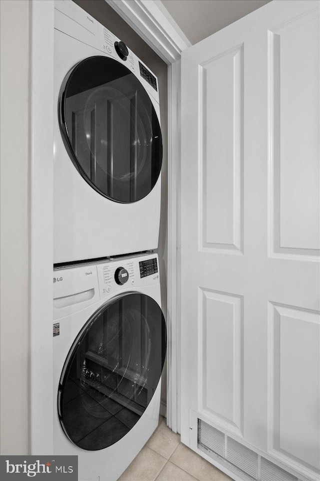 laundry area with light tile patterned floors, laundry area, visible vents, and stacked washer / drying machine