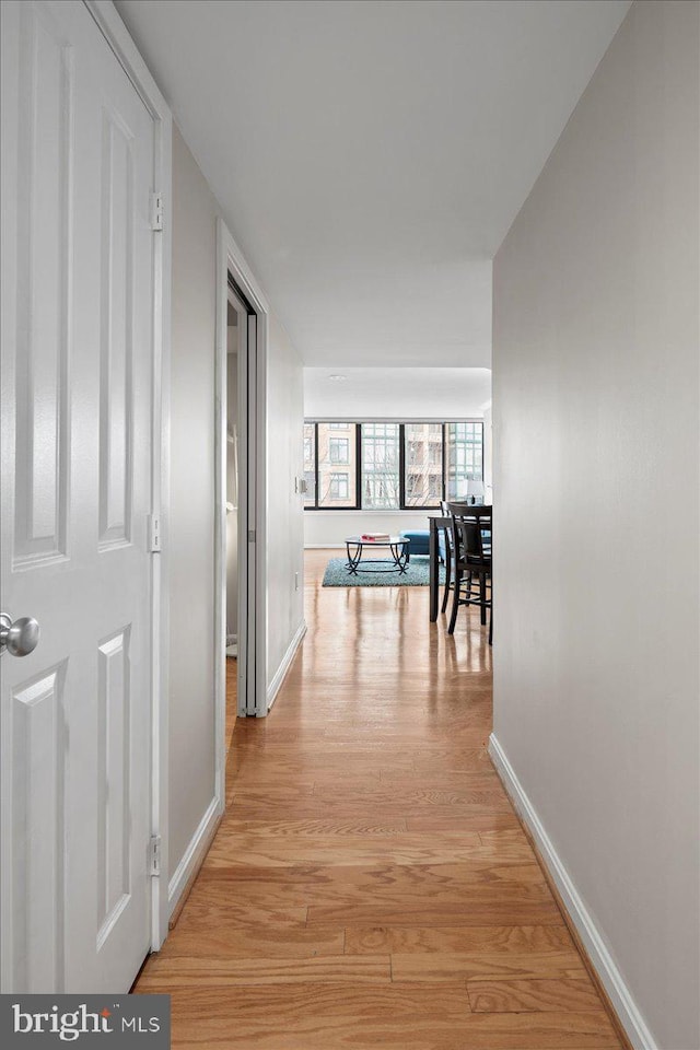 hallway featuring light wood-style flooring and baseboards