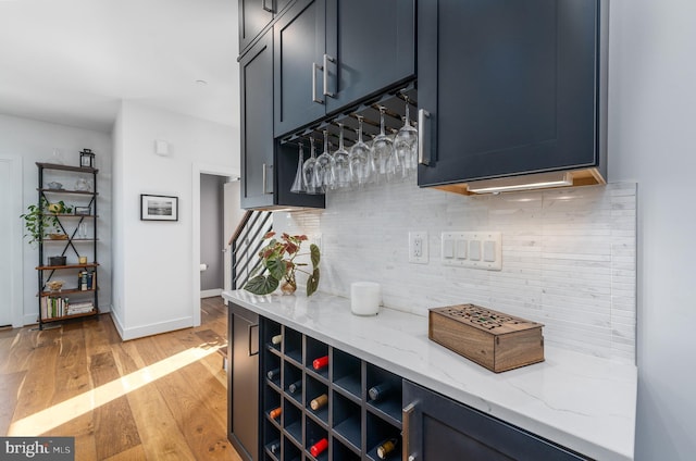 bar featuring tasteful backsplash, stairway, light wood-type flooring, and baseboards