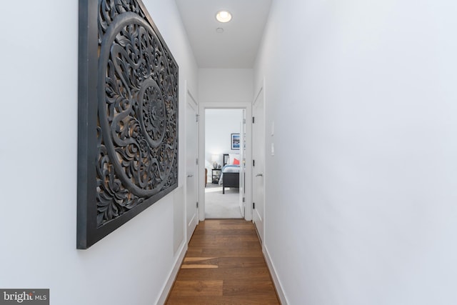 corridor with dark wood-type flooring, recessed lighting, and baseboards