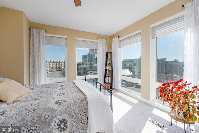 bedroom featuring access to outside, carpet flooring, a ceiling fan, and a city view