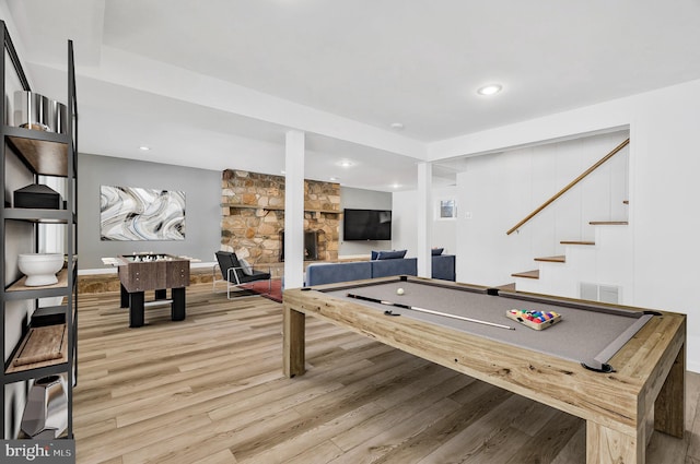 rec room with billiards, hardwood / wood-style flooring, and a stone fireplace