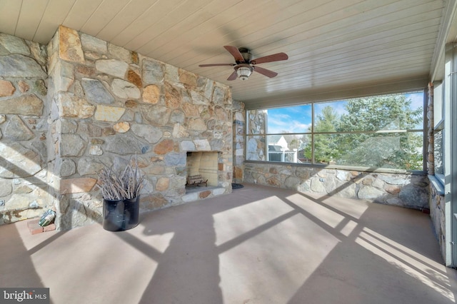 unfurnished sunroom featuring a fireplace, ceiling fan, and wood ceiling