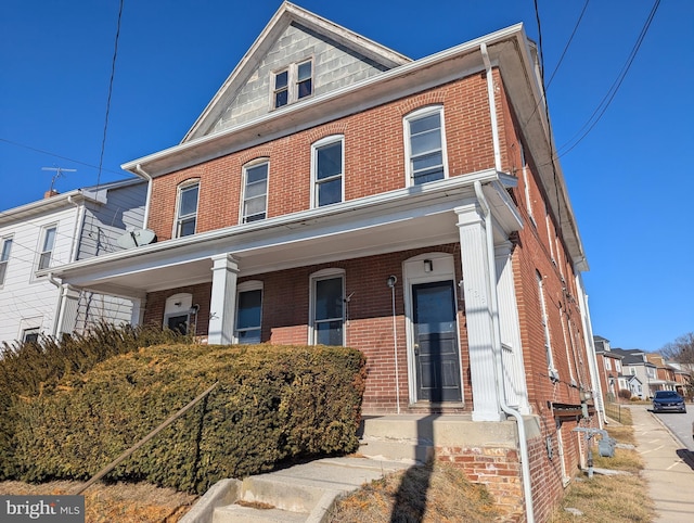 view of front of house featuring brick siding and a porch