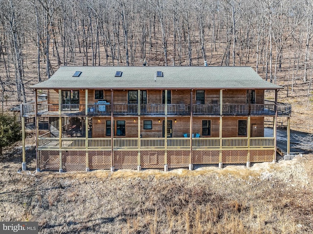 rear view of house featuring roof with shingles and a wooden deck