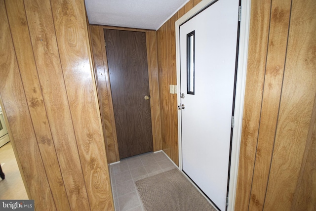 entryway featuring wood walls and light tile patterned floors