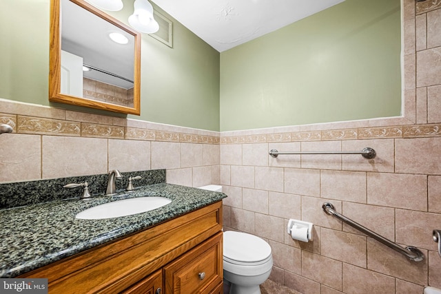 bathroom with tile walls, toilet, and vanity