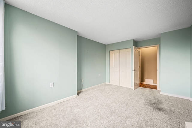 unfurnished bedroom with carpet, a closet, and a textured ceiling