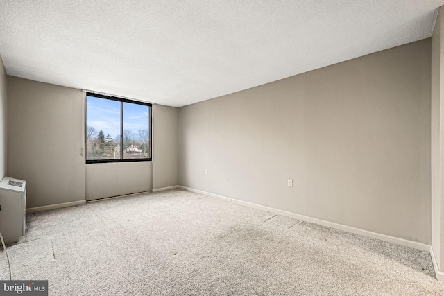 carpeted empty room featuring a textured ceiling