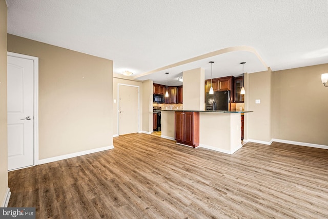 kitchen with hanging light fixtures, a textured ceiling, black appliances, and hardwood / wood-style floors