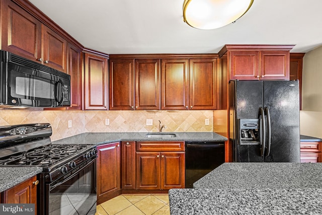 kitchen with dark stone counters, sink, black appliances, and backsplash