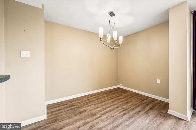 empty room featuring hardwood / wood-style floors, an inviting chandelier, and a textured ceiling