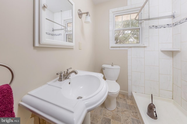 bathroom featuring tiled shower and toilet