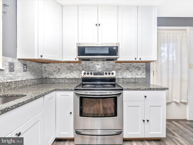 kitchen with white cabinets, appliances with stainless steel finishes, stone counters, and light hardwood / wood-style flooring