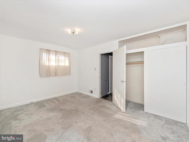 unfurnished bedroom with a closet and light colored carpet