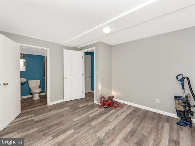 unfurnished bedroom with hardwood / wood-style flooring and connected bathroom