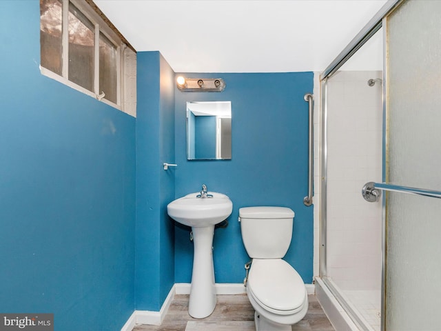 bathroom with toilet, hardwood / wood-style flooring, and a shower with door