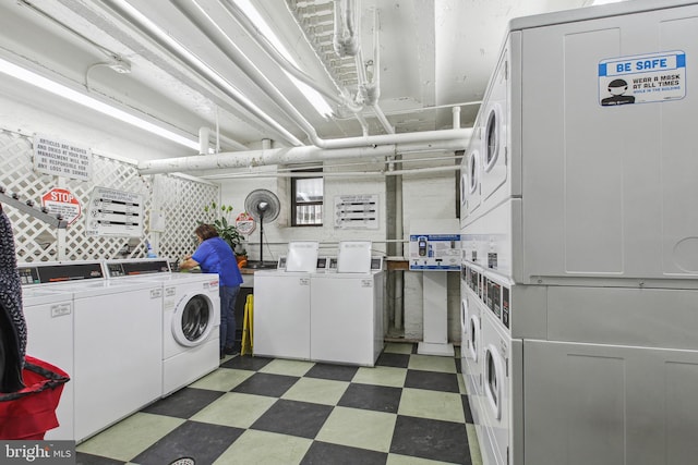 community laundry room featuring light floors, stacked washer / drying machine, and washing machine and clothes dryer