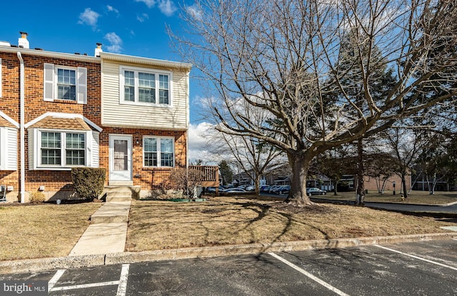 view of front of property with a front yard, uncovered parking, and brick siding