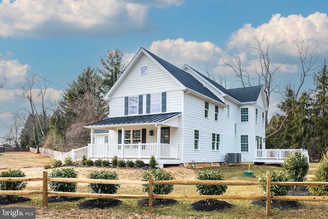 view of front facade with a standing seam roof, metal roof, a porch, and a fenced front yard