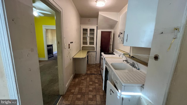 kitchen featuring ceiling fan, sink, white cabinetry, and washer / dryer