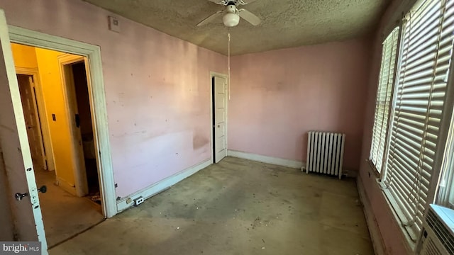 empty room featuring ceiling fan, a textured ceiling, and radiator heating unit