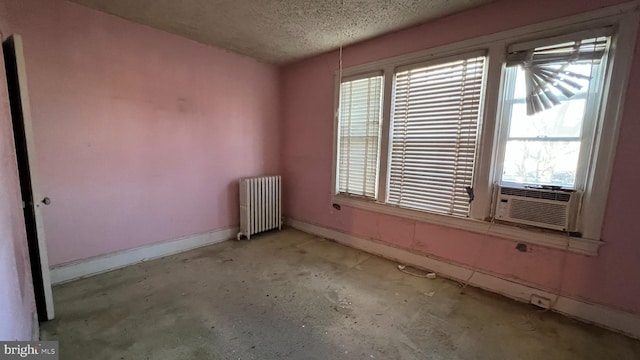 unfurnished room featuring cooling unit, a textured ceiling, and radiator heating unit