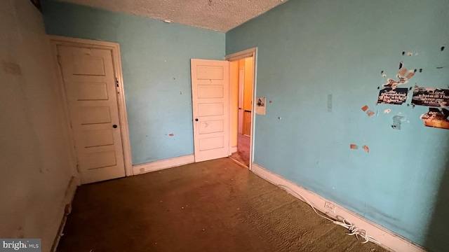 unfurnished bedroom featuring dark carpet and a textured ceiling