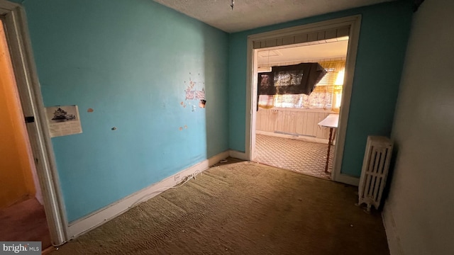 hall featuring carpet flooring, radiator, and a textured ceiling