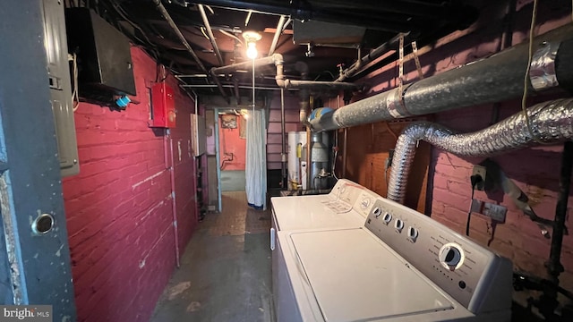 basement with gas water heater, washing machine and clothes dryer, and brick wall