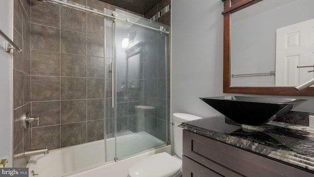 full bathroom featuring vanity, bath / shower combo with glass door, and toilet