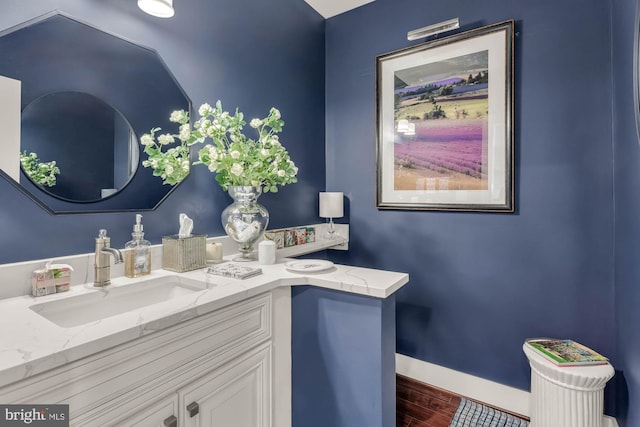 bathroom with wood finished floors, vanity, and baseboards