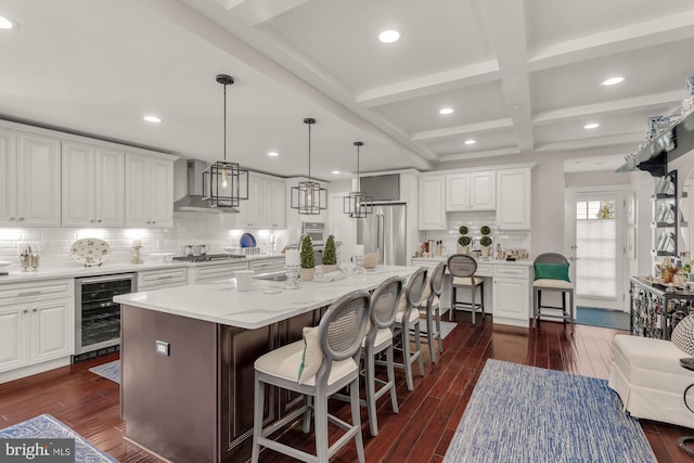 kitchen with wall chimney range hood, beverage cooler, appliances with stainless steel finishes, and dark wood finished floors