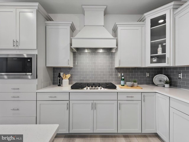33423 Hickory St, Millsboro, DE 19966 - kitchen featuring stainless steel microwave, light countertops, decorative backsplash, custom exhaust hood, and gas stovetop