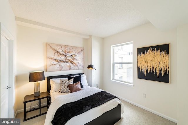 bedroom with carpet floors, baseboards, and a textured ceiling