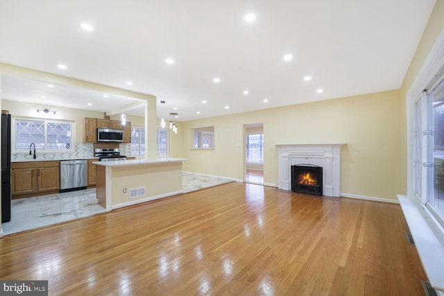 kitchen featuring a center island, stainless steel appliances, light countertops, visible vents, and open floor plan