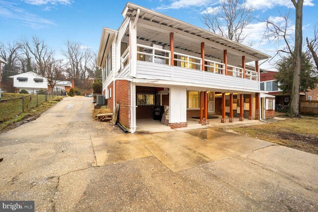 back of property featuring brick siding, fence, driveway, and central air condition unit