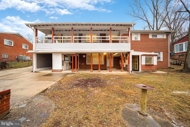 view of front facade with driveway, central air condition unit, a patio, and brick siding